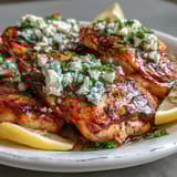 Sliced Greek Chicken with Lemon and Feta on a white plate, showing a golden sear and crumbled feta melting slightly.