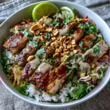 Golden sautéed chicken and fresh cilantro top fluffy coconut rice in a vibrant Peanut Chicken Protein Bowl.