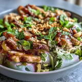 Vibrant Vietnamese-inspired bowl featuring silky rice paper shards, fresh herbs, and a creamy peanut sauce drizzle for a light meal.