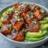 Zesty Avocado Salmon Bowl drizzled with spicy chili oil and topped with crunchy roasted peanuts.