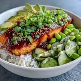 A finished Honey Sriracha Salmon Bowl featuring a spicy-sweet glaze on flaky fish, creamy avocado slices, and a drizzle of sriracha mayo.