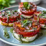 Classic Italian Caprese salad with vibrant tomatoes, mozzarella, and fragrant basil oil for a refreshing summer appetizer.  
