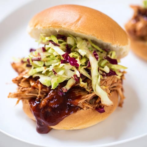 Golden, saucy BBQ chicken sliders on toasted buns, topped with crunchy, creamy slaw for game day.  