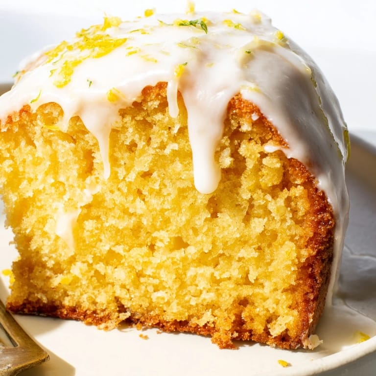 A slice of Lemon Pound Cake on a dessert plate with fresh berries, showcasing its moist, tender crumb and tangy glaze.