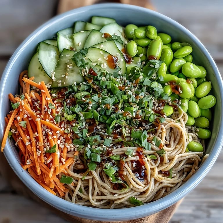 A close-up of a fresh soba noodle bowl with carrots, cucumber, and scallions, ready to enjoy for lunch or dinner.